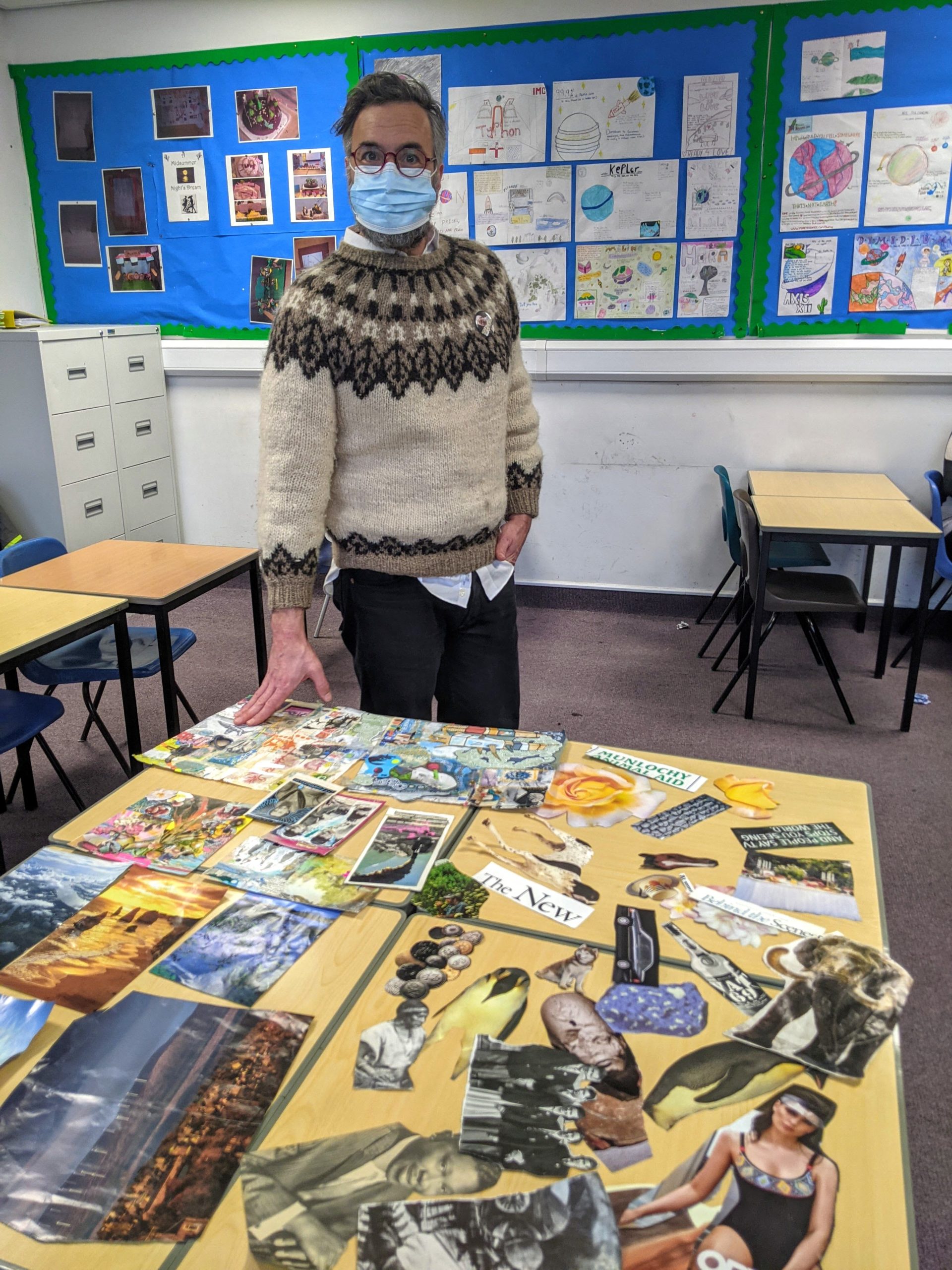 Ryan standing by a table of collaged images
